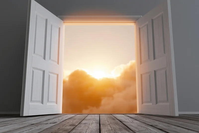 White double doors fully open to a sunrise sky viewed from a wooden floor interior