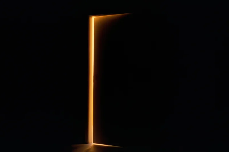 Slightly ajar interior door glowing with warm light in dark room