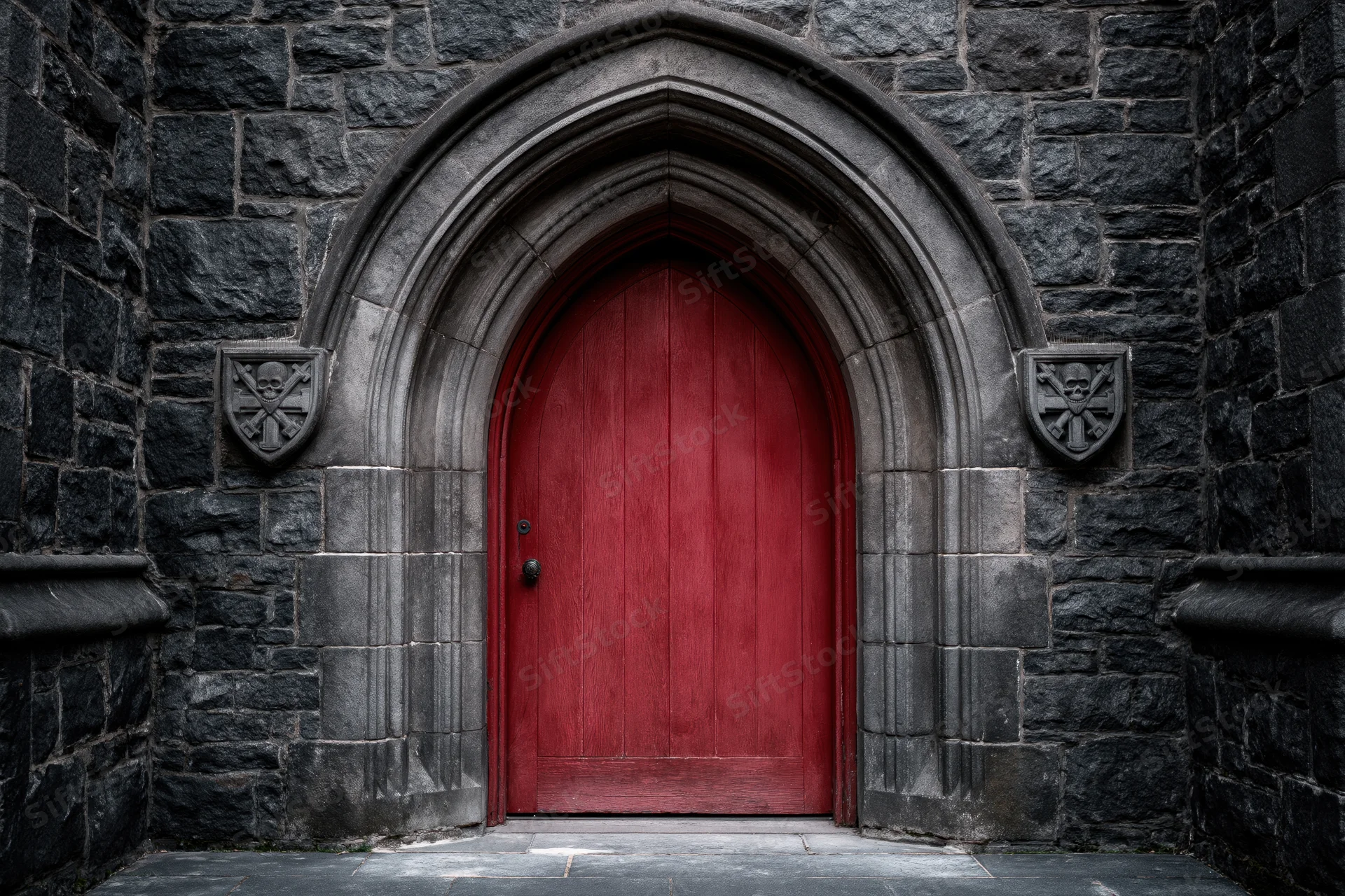 Red arched wooden door set within gothic stone archway of historic building