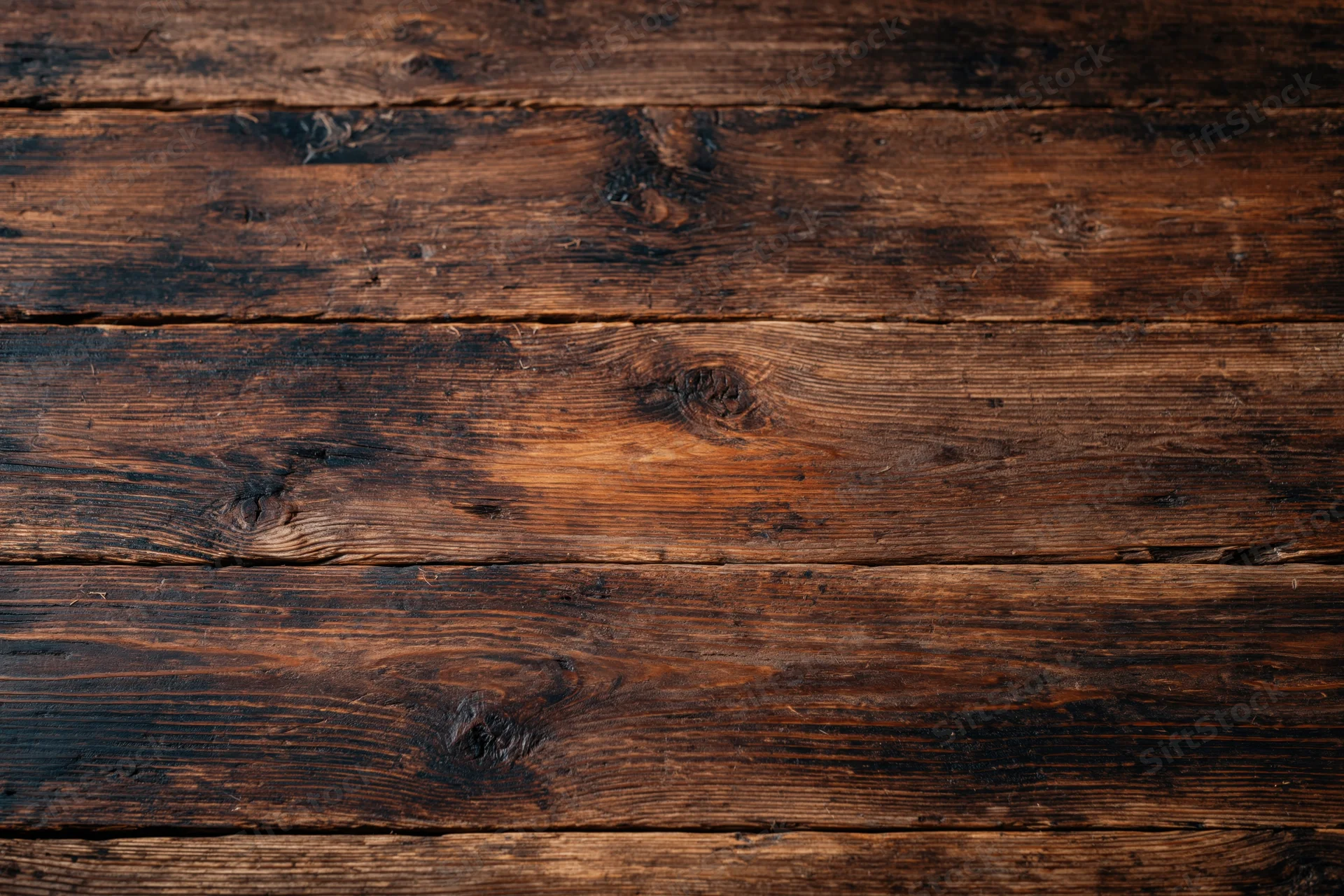 Dark aged wooden surface with horizontal planks and visible grain and knots filling the frame