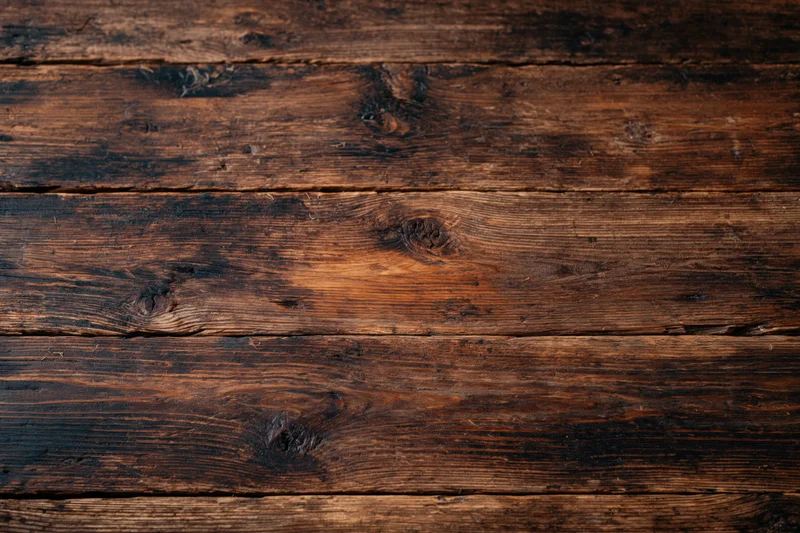 Dark aged wooden surface with horizontal planks and visible grain and knots filling the frame