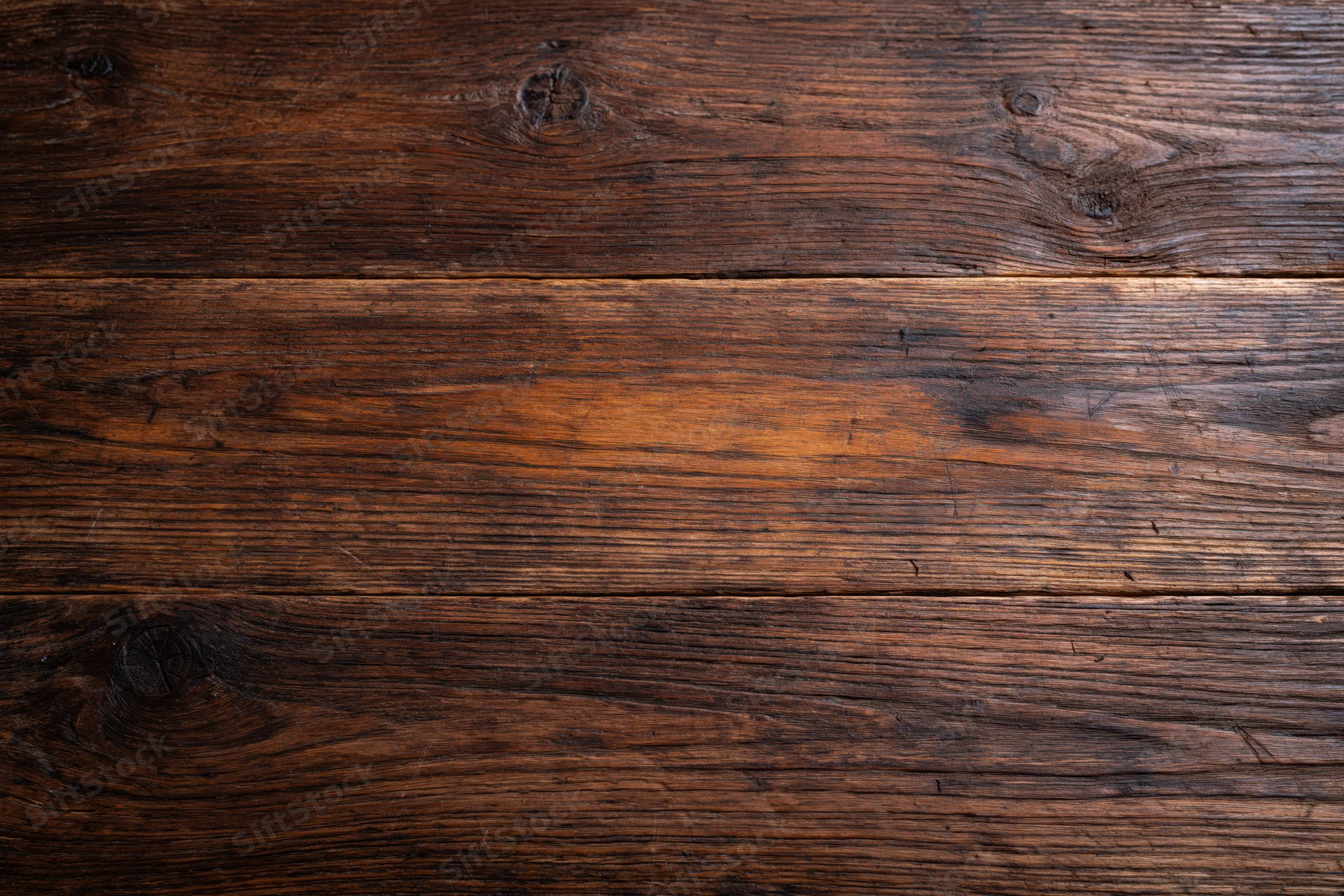 Dark aged wooden surface with visible grain and knots filling the frame