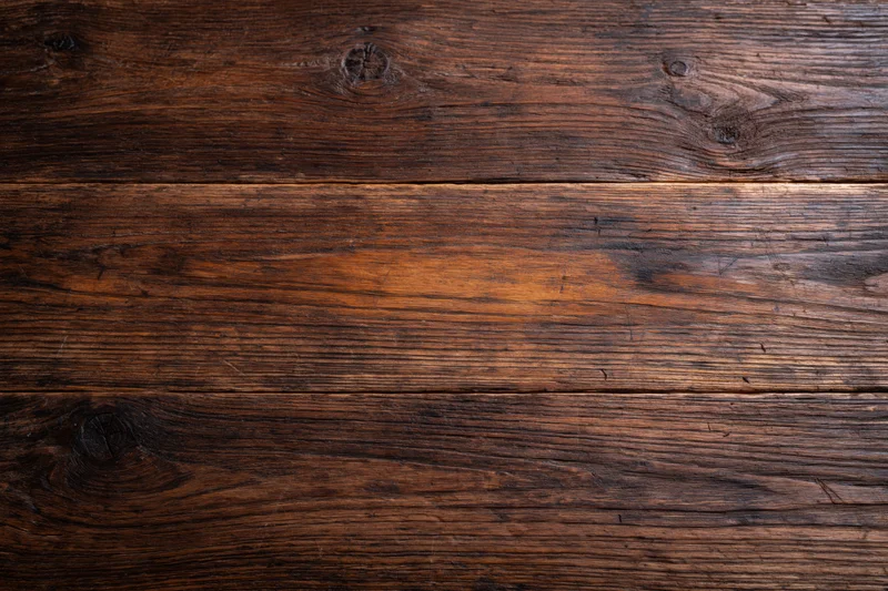 Dark aged wooden surface with visible grain and knots filling the frame