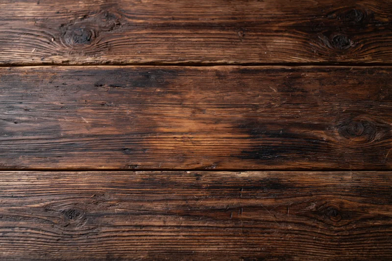 Dark aged wooden surface with visible grain and knots filling the frame in flat lay view