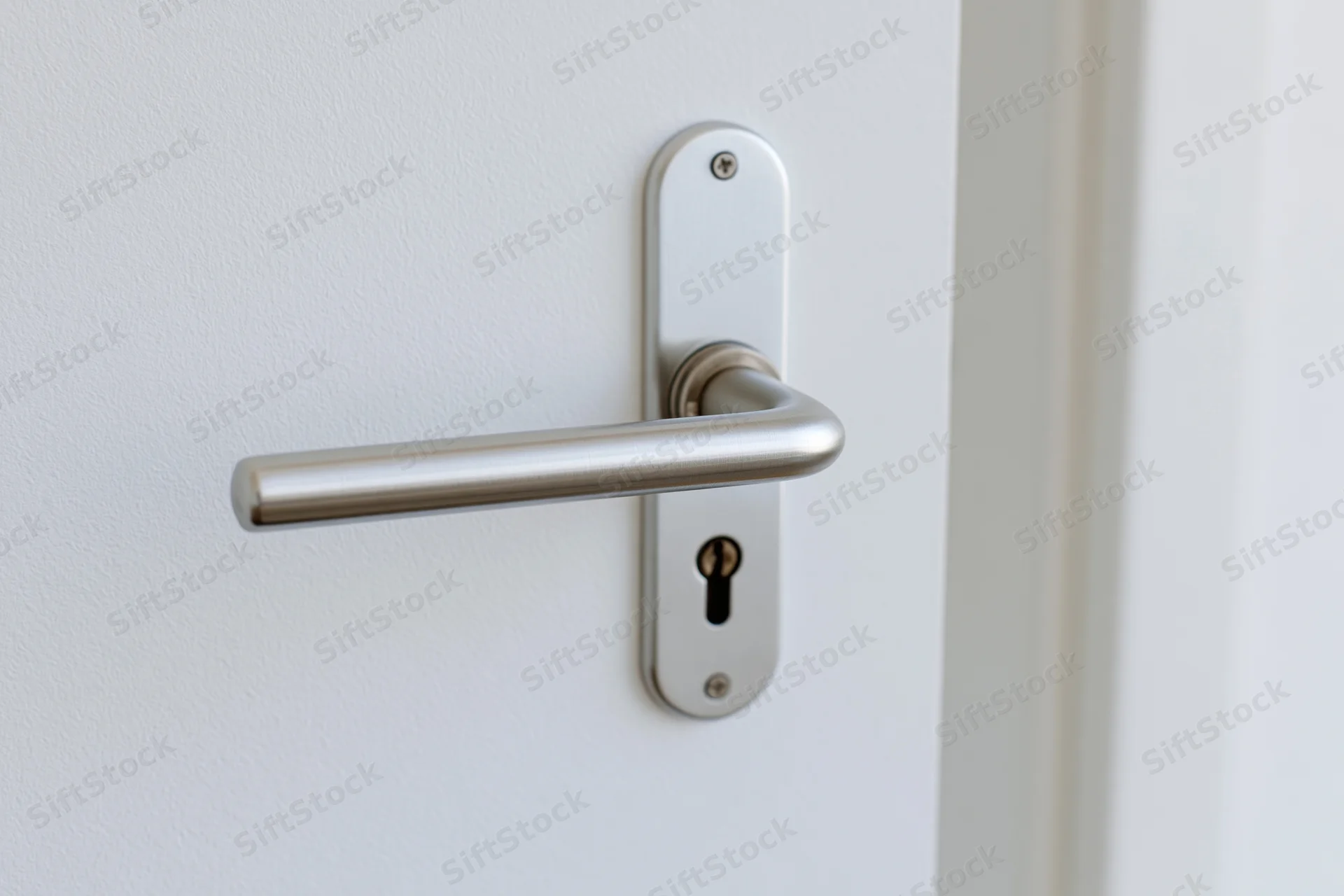 Brushed aluminum lever door handle with keyhole on white door