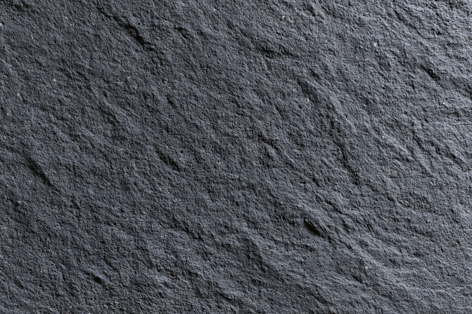 Close-up of dark charcoal concrete wall texture with rough surface and natural grain