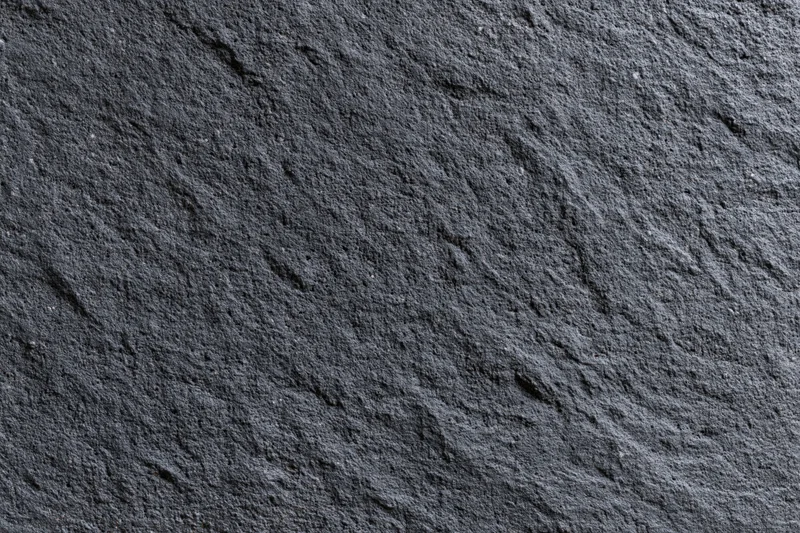 Close-up of dark charcoal concrete wall texture with rough surface and natural grain