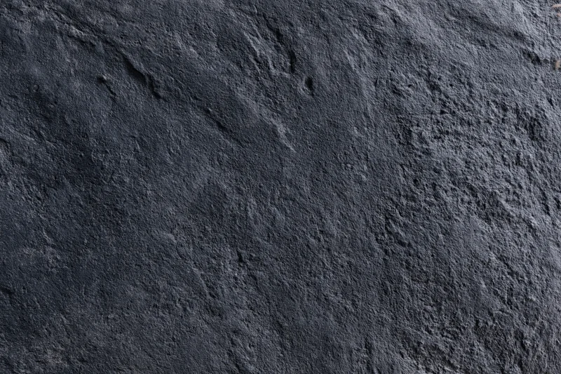 Close-up of dark charcoal concrete wall texture with rough uneven surface