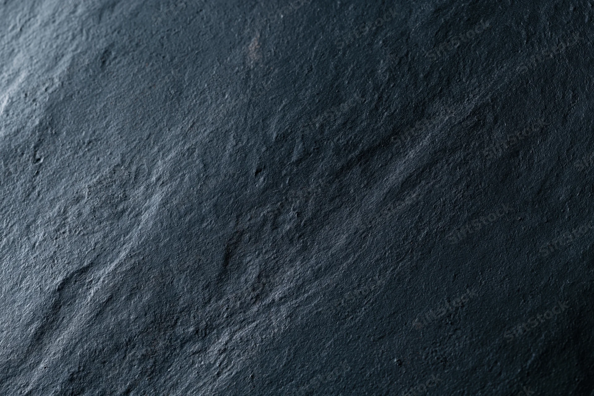 Close-up of dark charcoal concrete wall texture with rough uneven surface