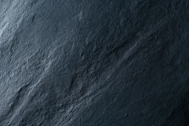 Close-up of dark charcoal concrete wall texture with rough uneven surface