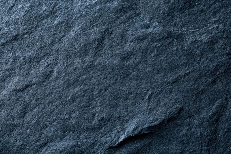 Close-up of dark slate stone surface with natural texture and cracks filling the frame