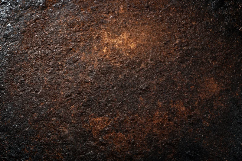 Close-up of a heavily oxidized metal surface with rough texture and dark brown rust patterns