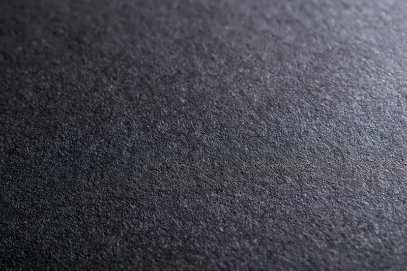 Close-up of dark charcoal grey textured paper surface in flat lay arrangement