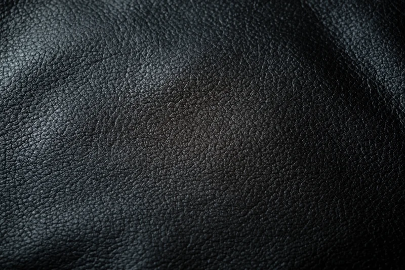 Close-up of dark charcoal leather surface showing fine grain texture