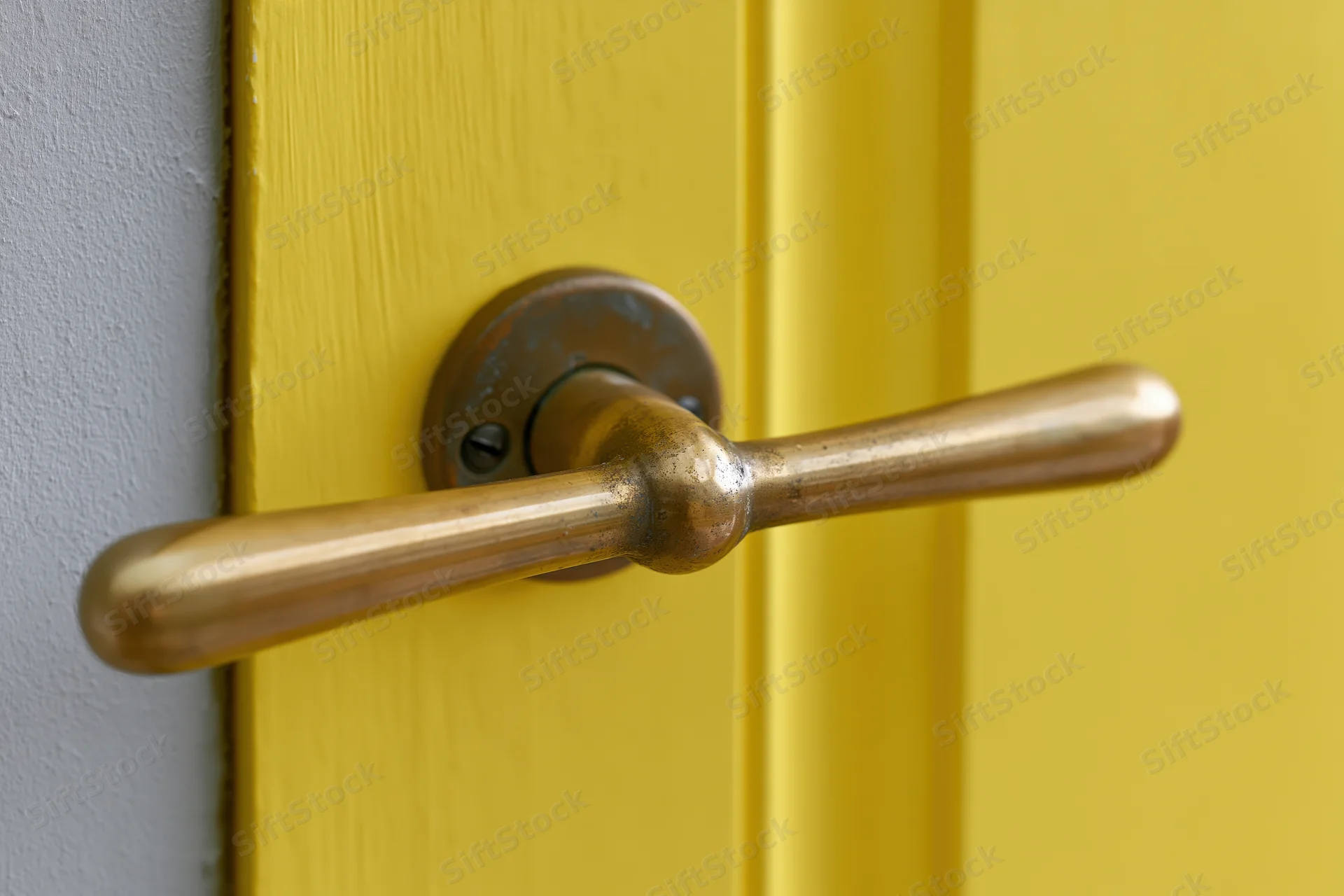 Brass lever door handle on a yellow wooden door