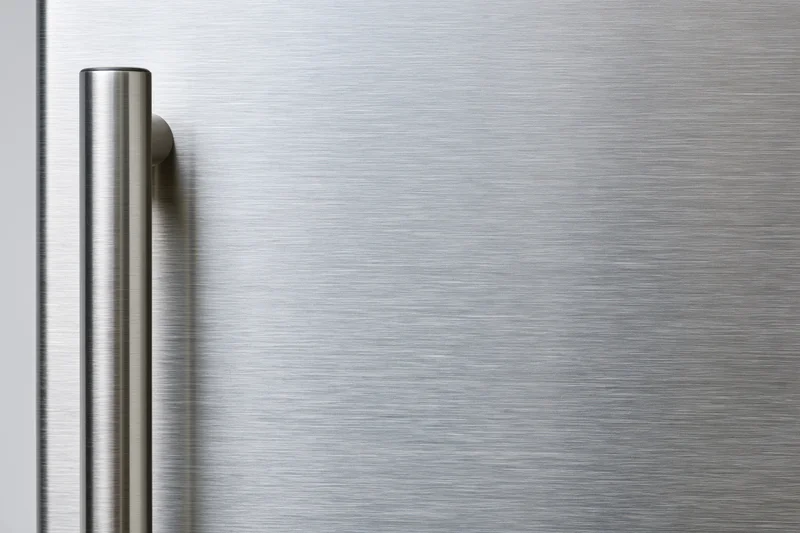 Close-up of a brushed stainless steel refrigerator door with vertical handle