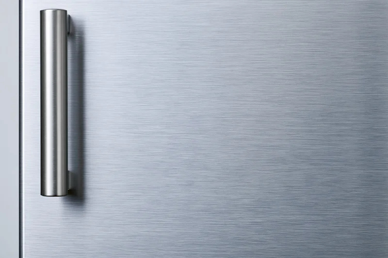Close-up of a brushed stainless steel refrigerator door with a vertical handle on the left side