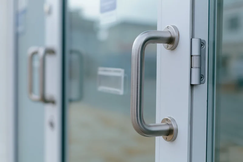Close-up of a commercial glass door with brushed aluminum handle and metal frame