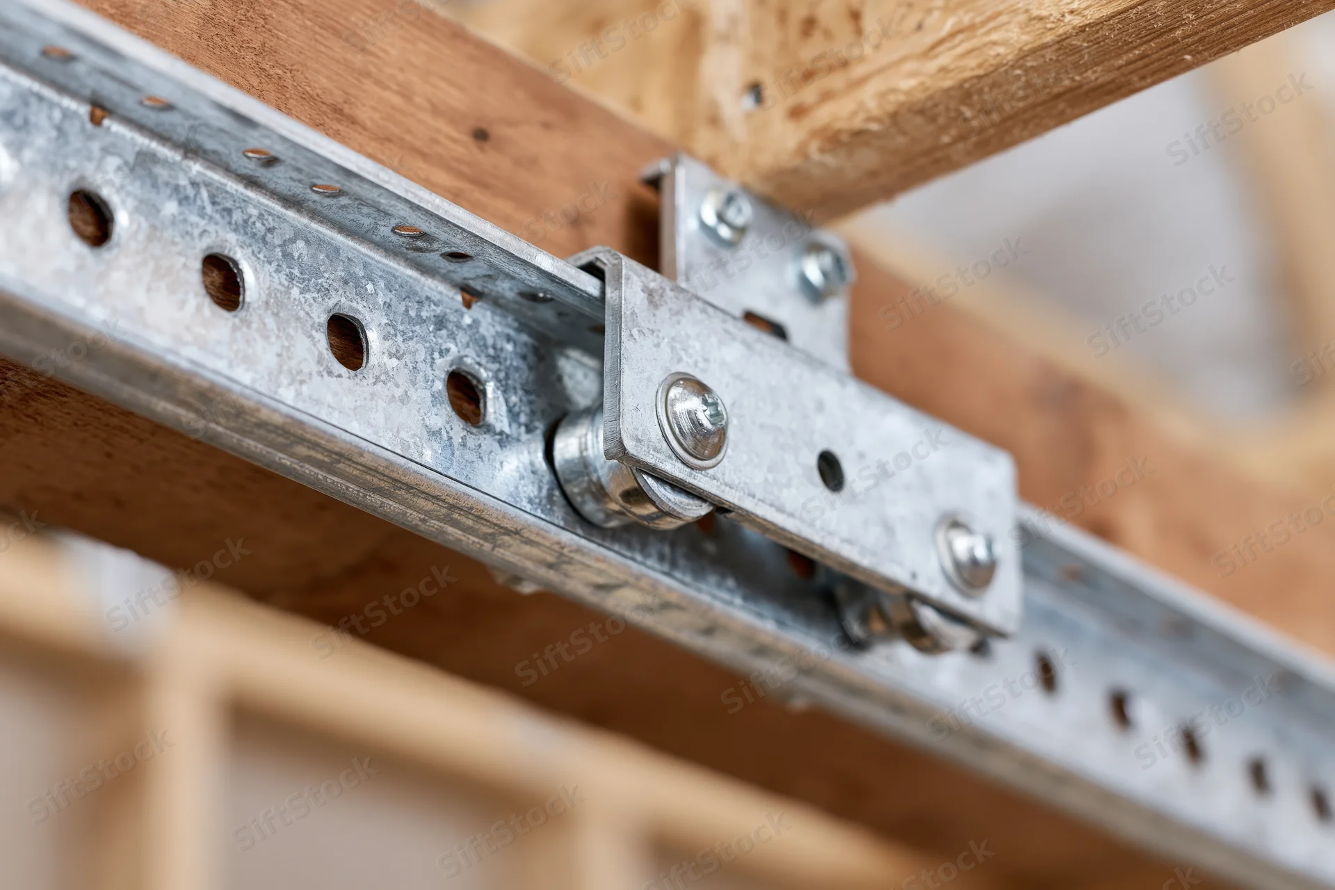 Close-up of galvanized steel garage door track and bracket attached to wooden beam
