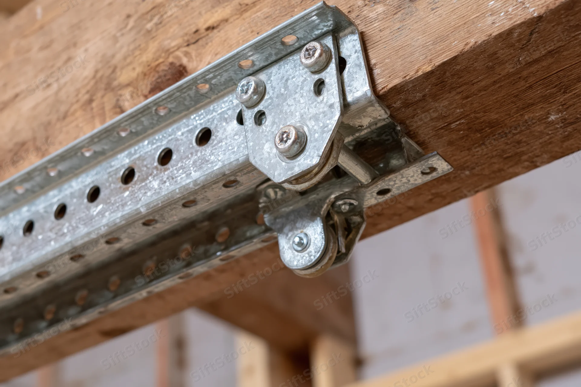 Galvanized steel garage door track and bracket attached to wooden beam