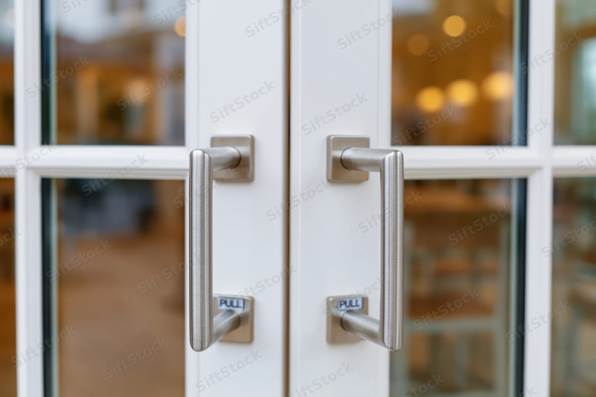 Close-up of double glass doors with stainless steel handles and pull signs
