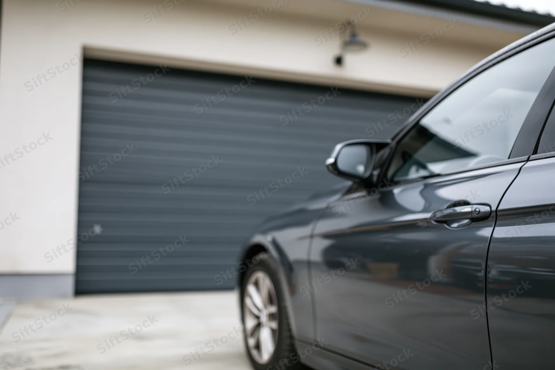 Dark grey sedan parked in front of residential garage door