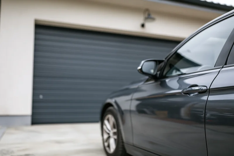 Dark grey sedan parked in front of residential garage door