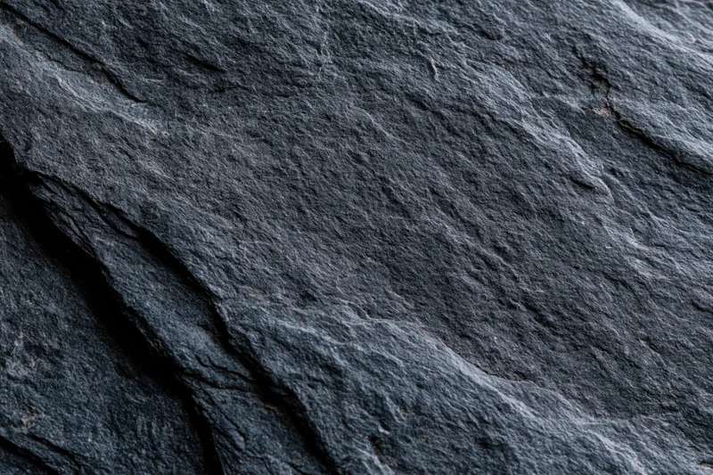 Dark slate rock surface with natural fractures and layered texture filling the frame