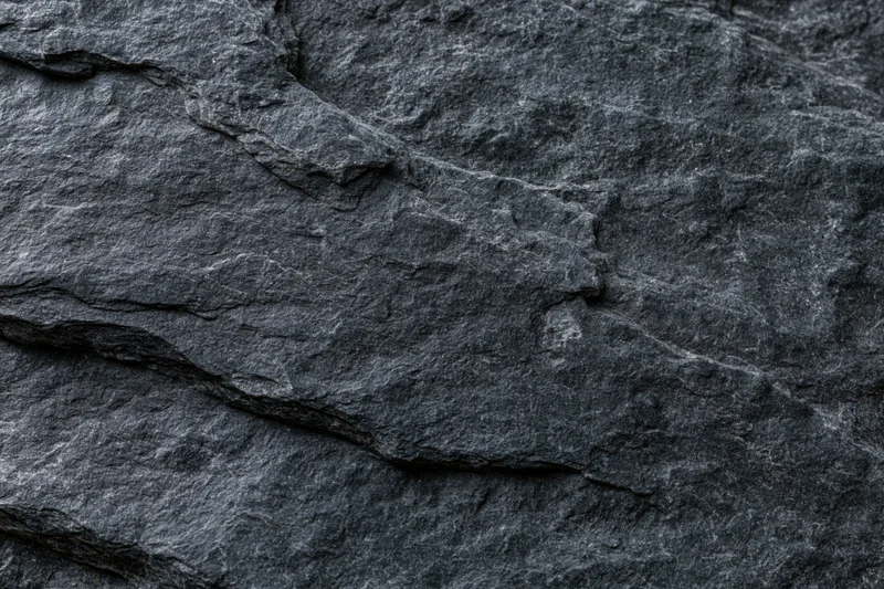 Dark slate rock surface with natural cracks and layers filling the frame