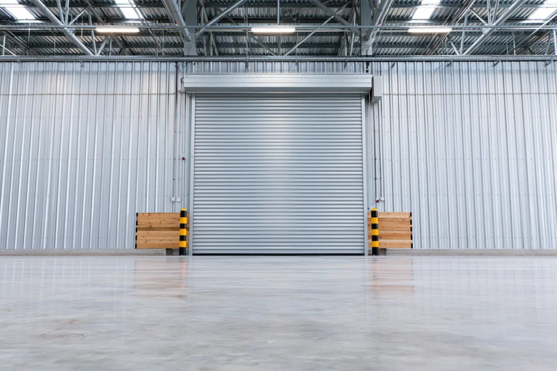 Empty industrial warehouse interior with closed metal roller shutter door