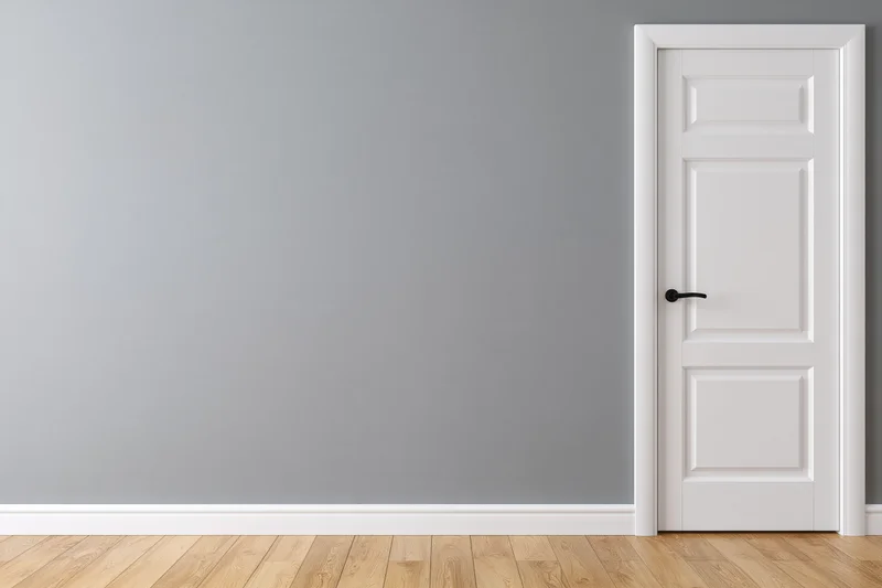 White three-panel door on gray wall in empty room with wooden floor