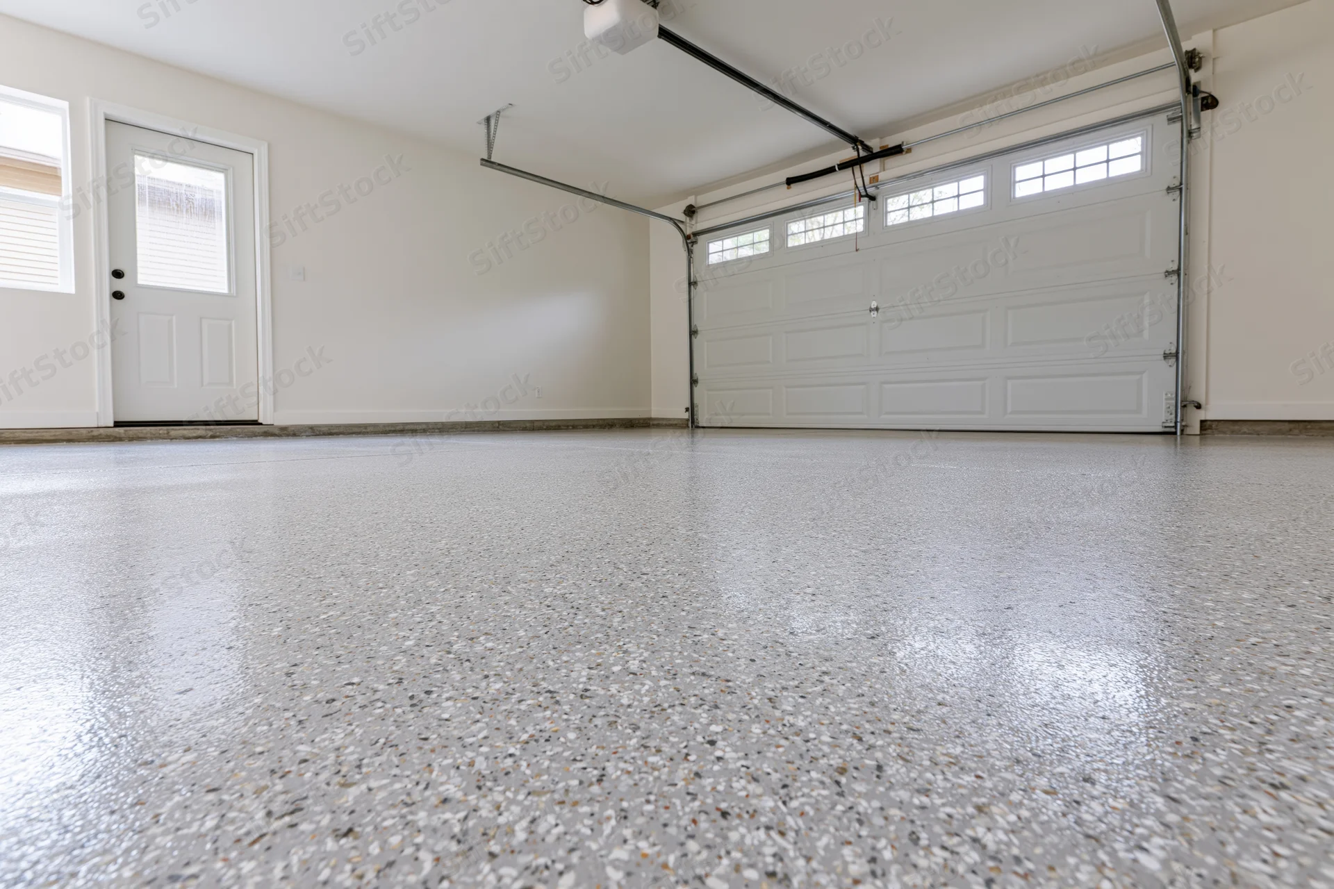 Empty residential garage interior with polished epoxy floor and white sectional door