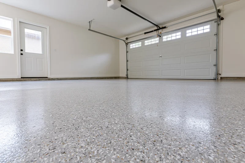 Empty residential garage interior with polished epoxy floor and white sectional door