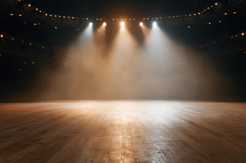 Empty theater stage with polished hardwood floor illuminated by spotlights