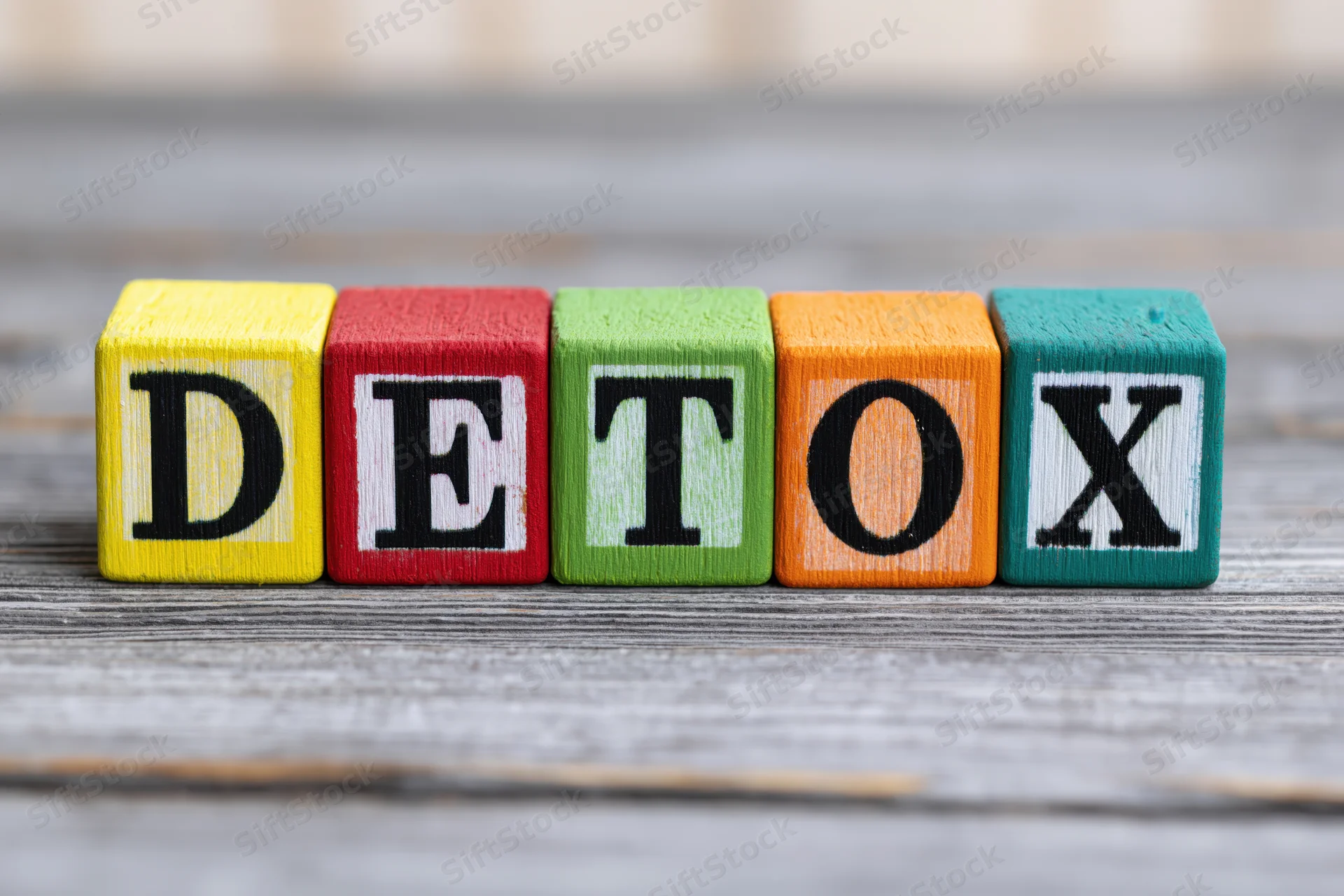 Colorful wooden blocks spelling detox arranged on a gray wooden surface
