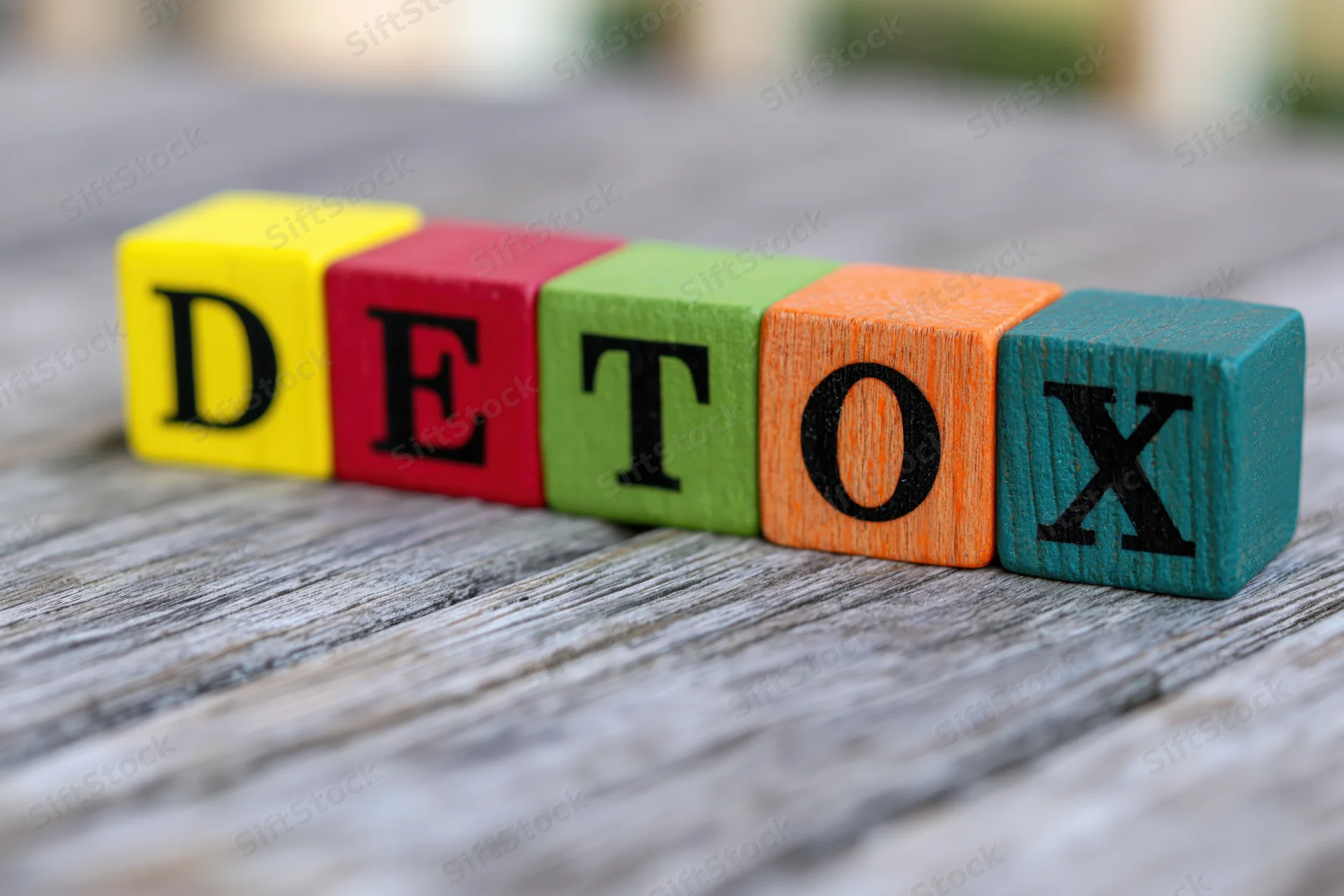 Colorful wooden blocks spelling detox arranged on a weathered wooden surface