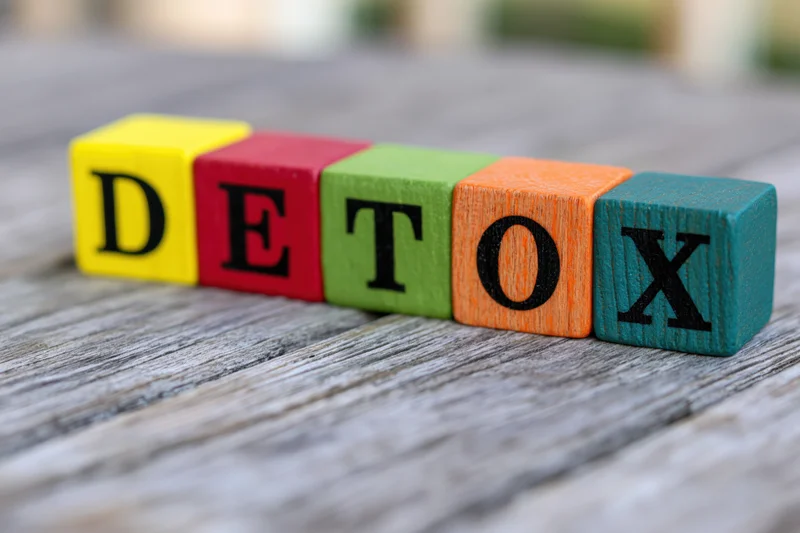 Colorful wooden blocks spelling detox arranged on a weathered wooden surface