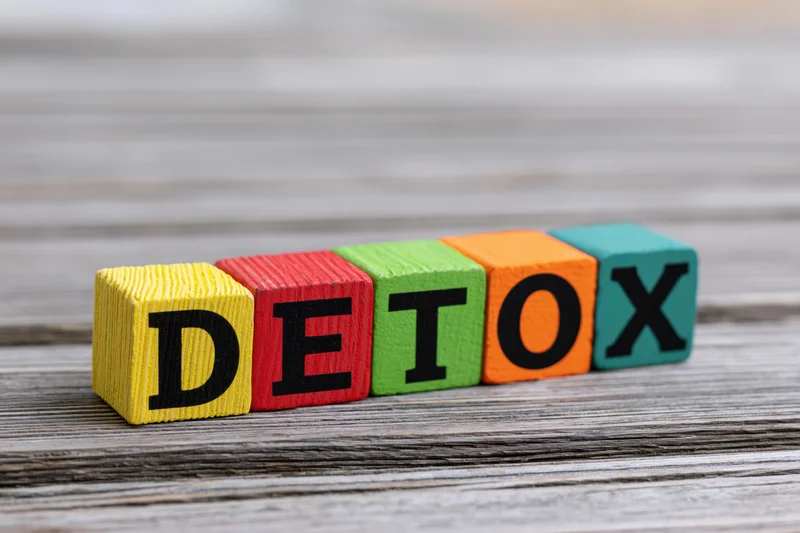 Colorful wooden blocks spelling detox arranged in a row on a weathered wood surface