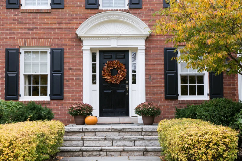 Colonial home front entrance with autumn wreath and pumpkin on stone steps
