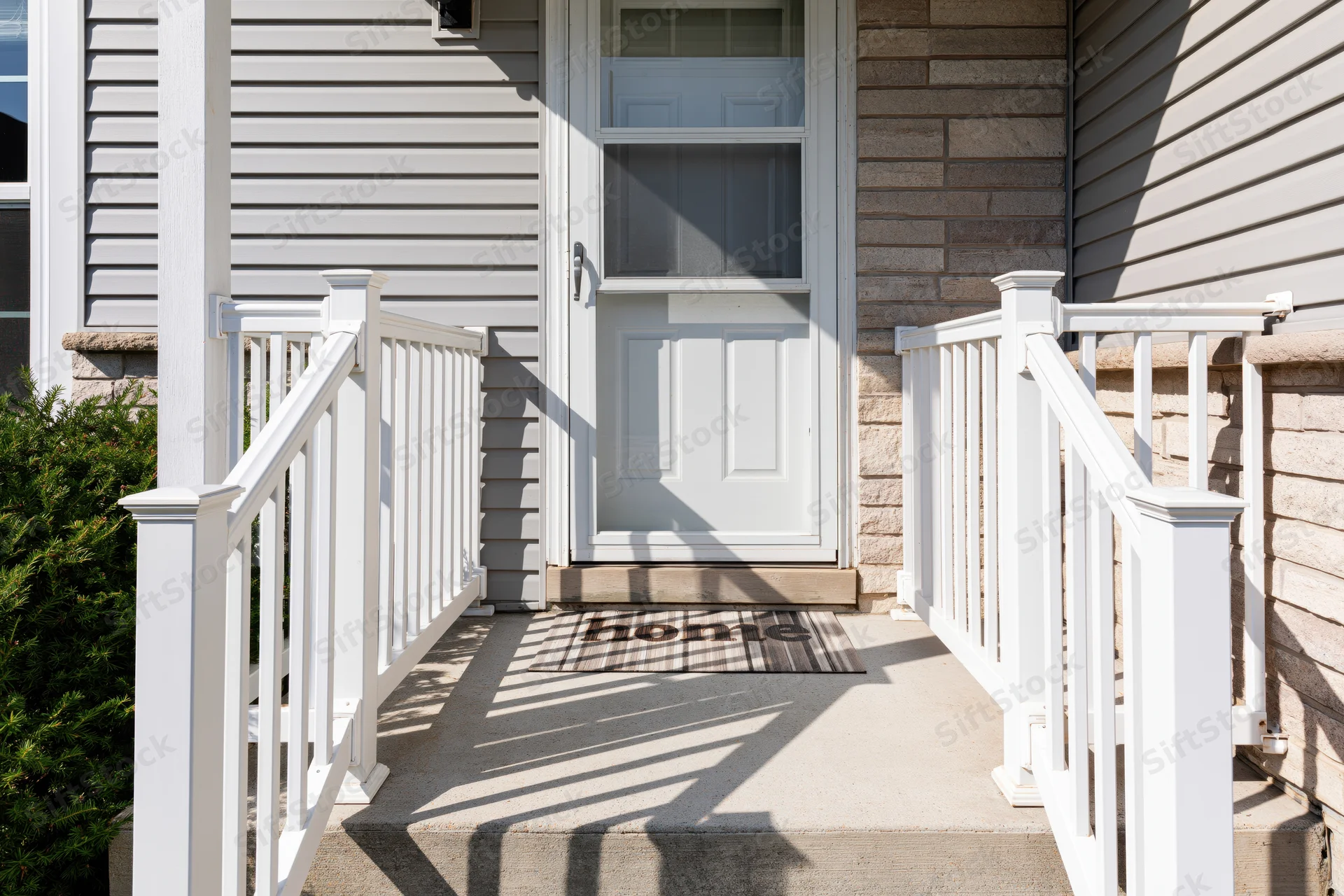 Front entrance of a suburban home with white door and steps leading to a porch with railing and welcome mat
