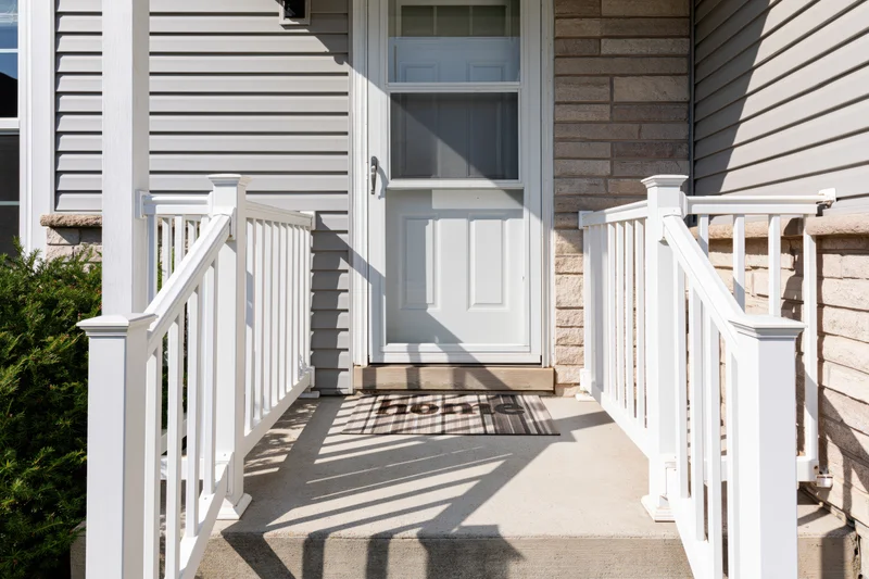 Front entrance of a suburban home with white door and steps leading to a porch with railing and welcome mat