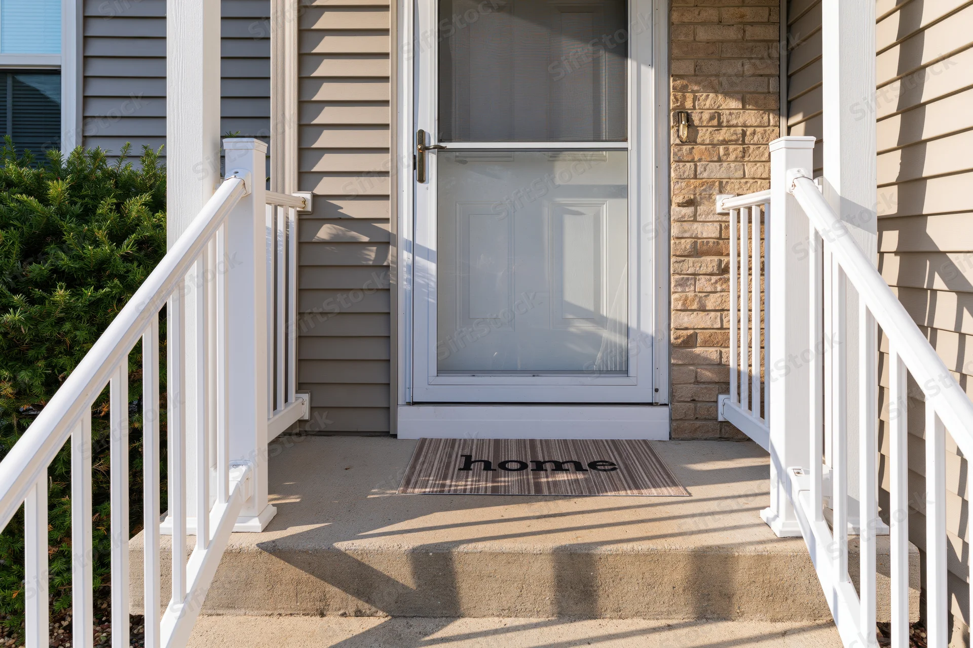 Front entrance of a suburban home with white railing and welcome mat on steps