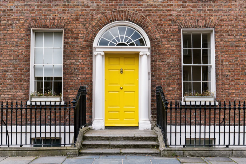Georgian townhouse facade with bright yellow door and black iron railing