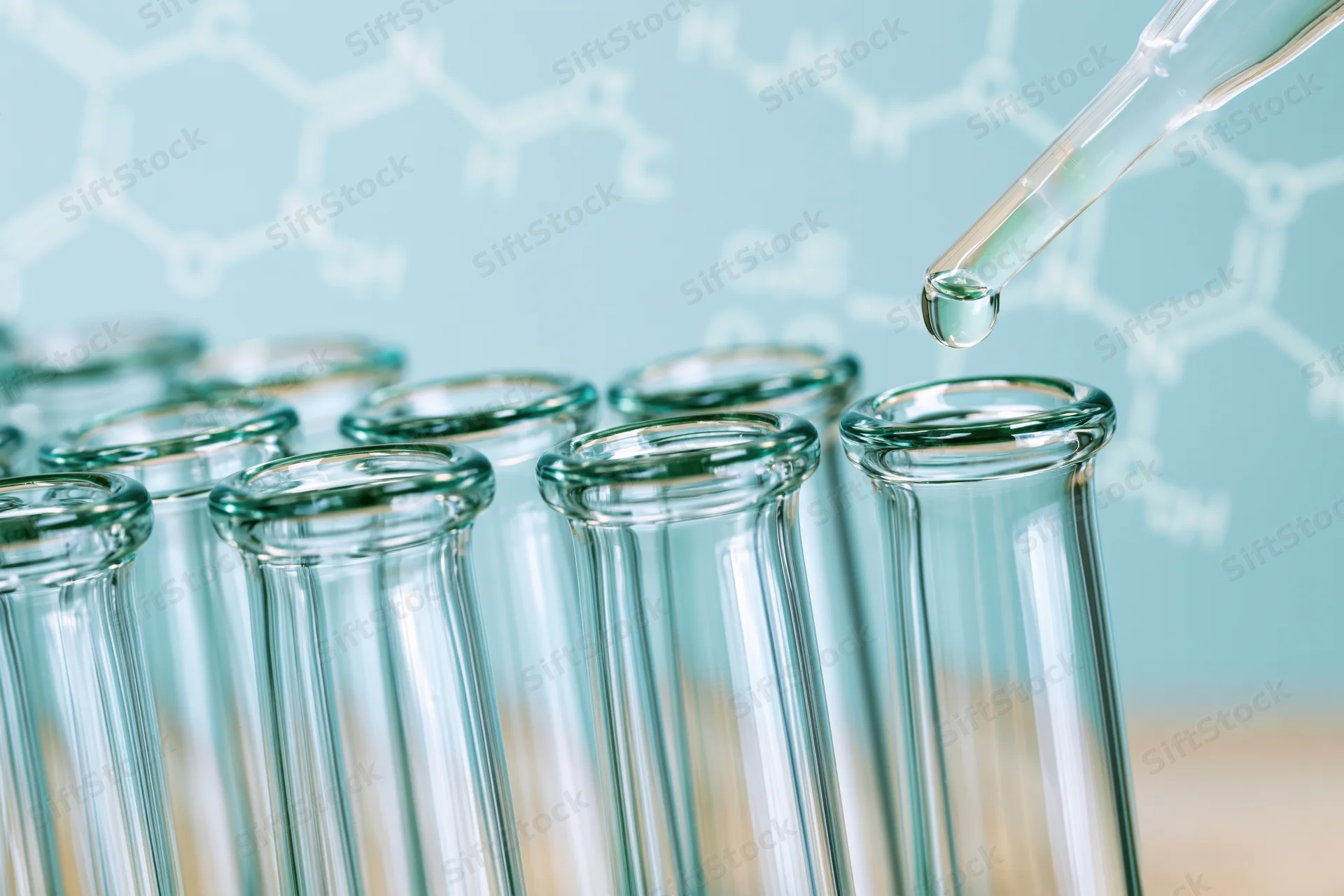 Pipette dropping liquid into a row of glass test tubes in a laboratory setting