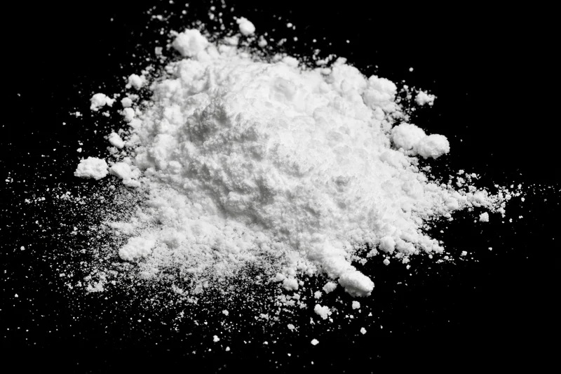 White powder scattered and spilled on black surface