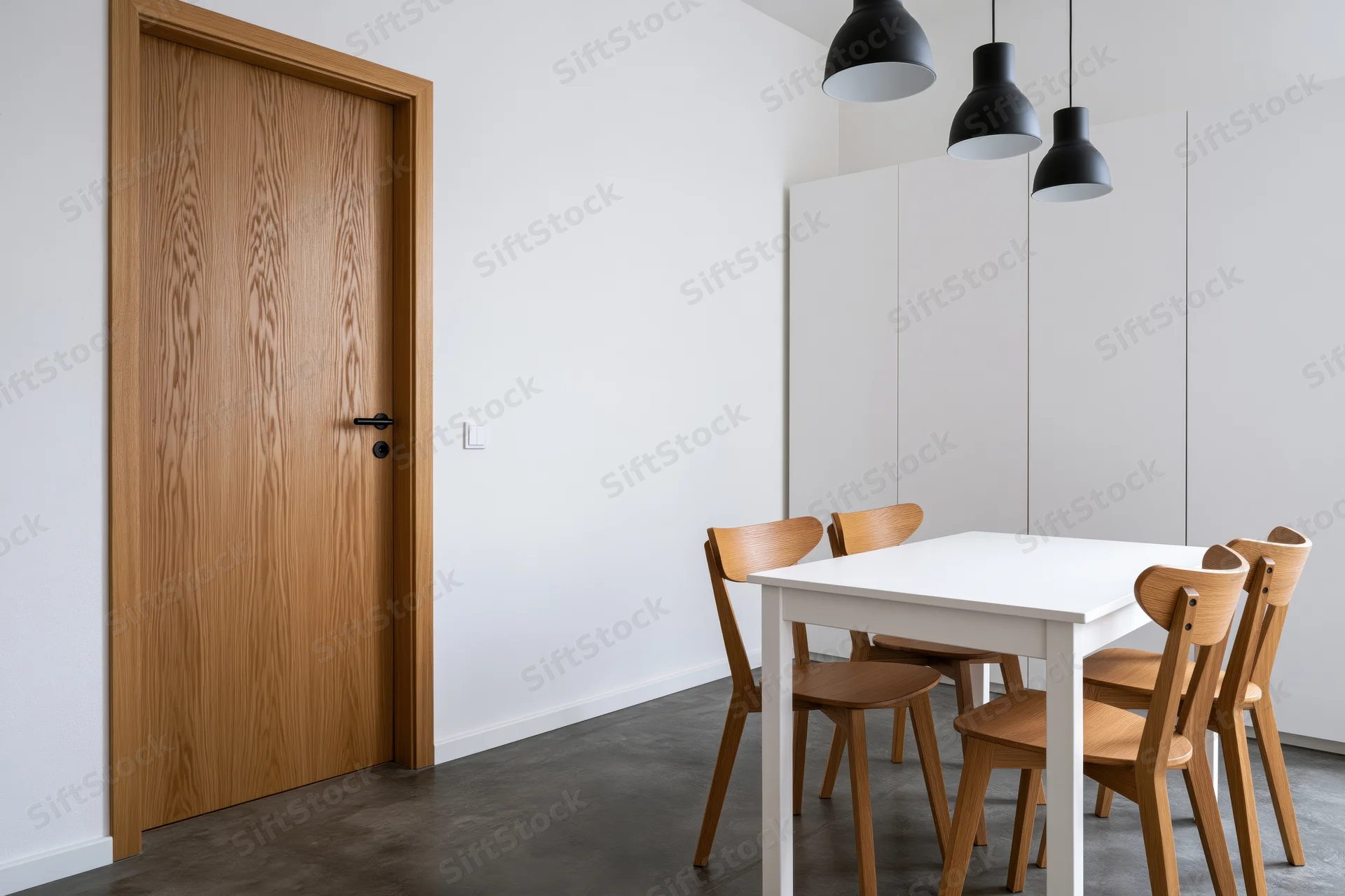 Minimalist dining area with white rectangular table and wooden chairs beside a door and cabinet