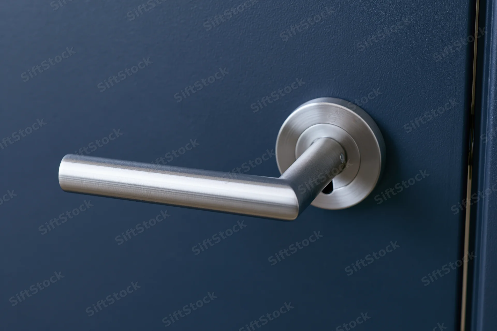Modern brushed stainless steel lever door handle on a blue door with keyhole