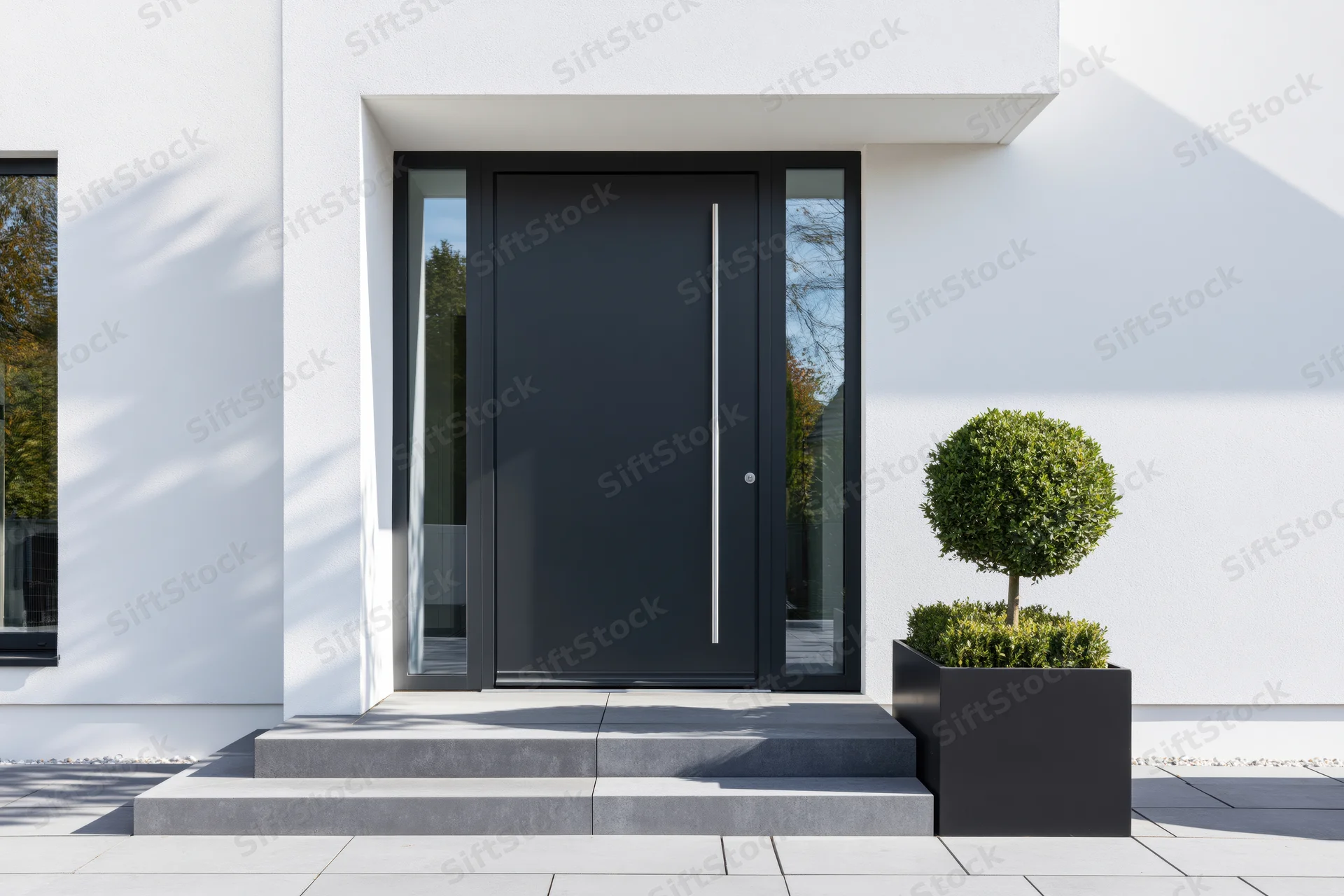 Modern residential entrance with dark charcoal pivot front door and minimalist landscaping