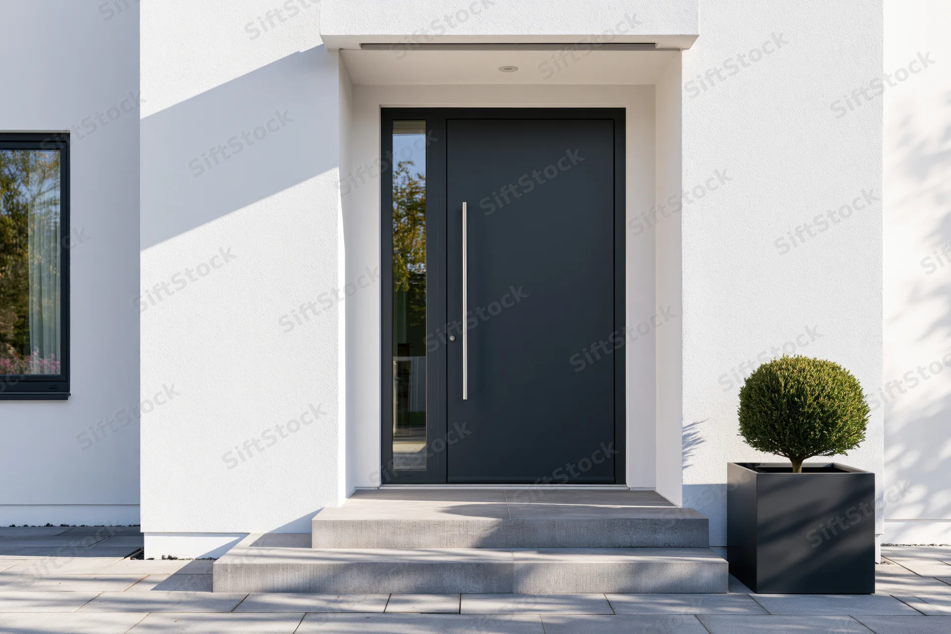 Modern residential entrance with charcoal pivot front door and white facade