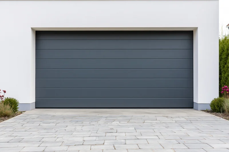 Modern residential garage with horizontal panel door on white facade and stone driveway